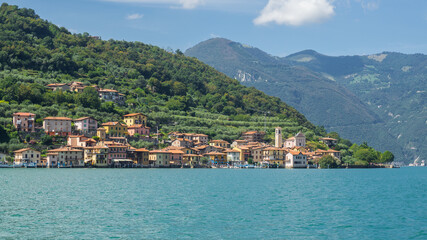 Fototapeta na wymiar The village of Carzano from the boat. Village located on the Island of Montisola. Lake Iseo. North Italy. Tourists destination