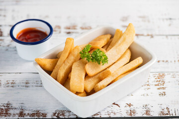 Tasty french fries on plate, on wood table background