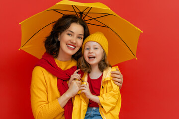 Family with umbrella on colored background.