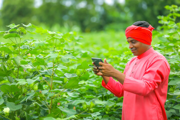 Young Indian farmer using mobile phone at Agriculture field