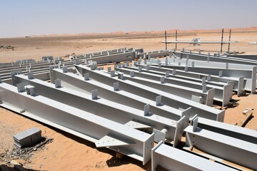 White painted steel structures on the desert ground. 