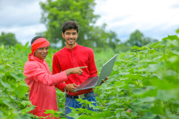 Young Indian farmer with agronomist at Cotton field , showing some information in laptop