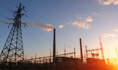 Fototapeta na wymiar High voltage power lines at sunset. Thermal power plant. High-voltage transformer substation