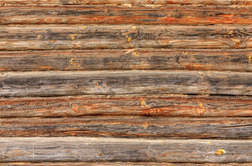 The wall of a log cabin with slightly burned logs. 