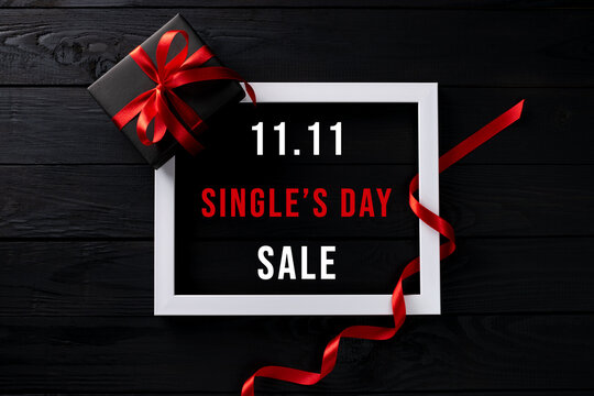 Online shopping of China, 11.11 singles day sale concept. Top view of white picture frame with black gift box on black wooden background with copy space for text 11.11 singles day sale.