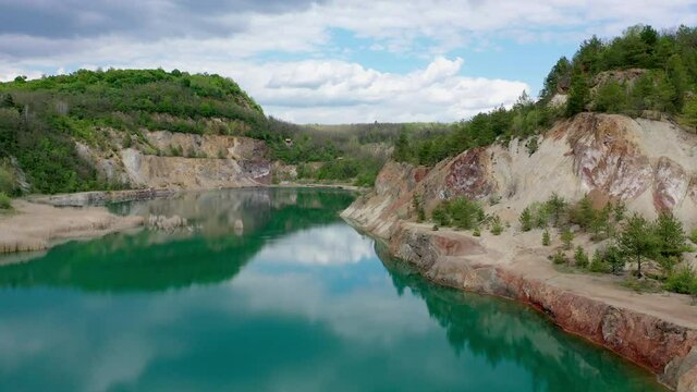 Old quarry lake with beautiful turquoise water. Forest surroundings and red colored cliffs