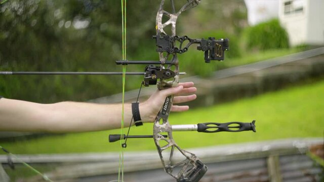 A side view of a compound bow being drawn and fired with a very shallow depth of field.