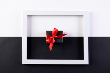 Gifts and white photo frame on black and white paper background. Black Friday concept.