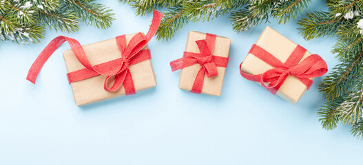 Christmas gift boxes and fir tree over blue background