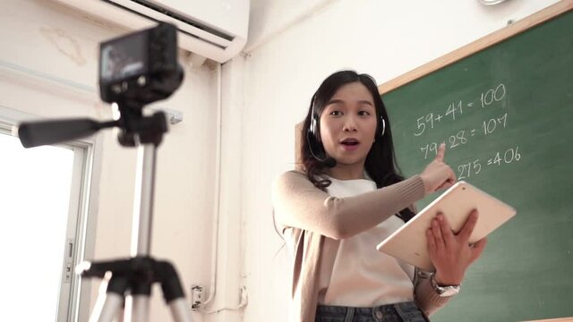 Asian woman teacher standing online teaching with headphone and digital tablet
