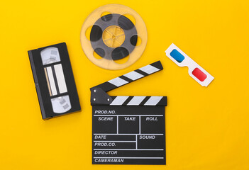 Movie clapper board, video cassette and film reel, 3d glasses on yellow background. Cinema...