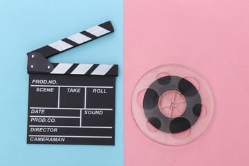 Movie clapper board and film reel on  pink blue pastel background. Cinema industry, entertainment. Top view