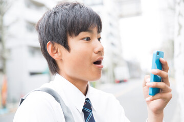 スマートフォンを見て驚く男子学生