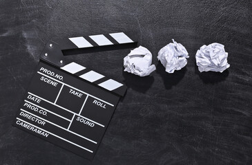 Movie clapper board and crumpled paper balls on chalk blackboard. Cinema industry, entertainment