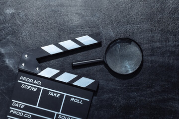 Movie clapper board and magnifying glass on chalk blackboard. Cinema industry, entertainment