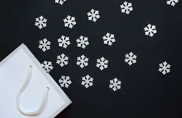 white snowflakes fly out of gift bag on dark background