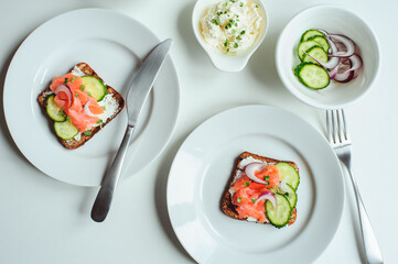tasty healthy breakfast - salmon and avocado toast with cream cheese, cucumber and red onion on white background