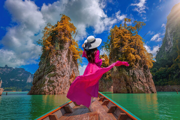 Beautiful girl standing on the boat and feel happy at Ratchaprapa Dam, Khao Sok National Park, Surat Thani Province, Thailand.