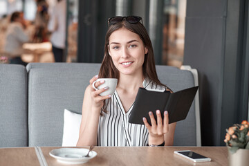 Young business woman in a cafe reading an ebook and drinking coffee