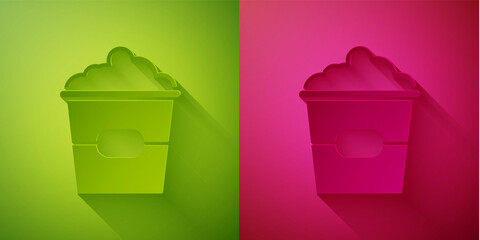 Paper cut Popcorn in cardboard box icon isolated on green and pink background. Popcorn bucket box. Paper art style. Vector Illustration.