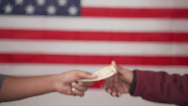 concept of buying votes in US election showing by exchanging I voted sticker with money on US flag as background