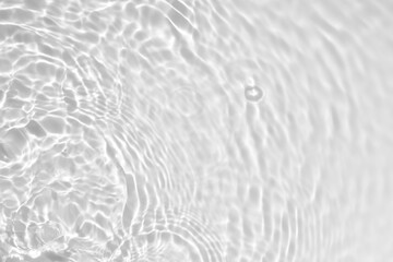 Blurred desaturated transparent clear calm water surface texture with splashes and bubbles. Trendy abstract nature background. White-grey water waves in sunlight. Copy space.