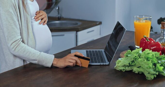 Cropped view of pregnant woman using laptop and credit card near vegetables 