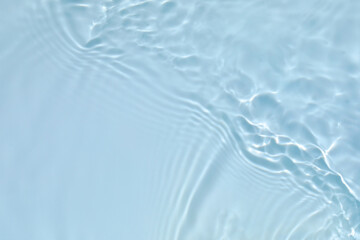 Fototapeta na wymiar Blurred transparent blue colored clear calm water surface texture with splashes and bubbles. Trendy abstract nature background. Water waves in sunlight with copy space.