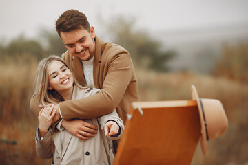 Couple in a autumn field. Lady drawing. Man in a brown coat.