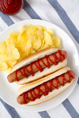Tasty American Hot Dog with Potato Chips on a white plate, top view. Flat lay, overhead, from above.