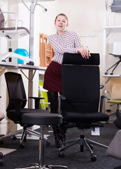 Stylish smiling girl standing among various chairs for sale in furniture shop