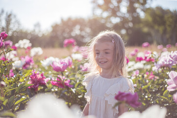 Little cute girl posing in peonies field.