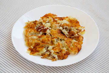 Homemade Fried Hashbrowns on a white plate, side view. Close-up.