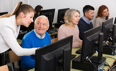 Computer lessons for adults. Young woman instructing smiling senior man in computer skills