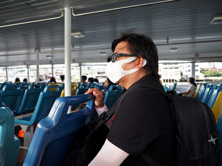 man with protective face mask sit sleeping on transfer boat, new normal, social distance travel