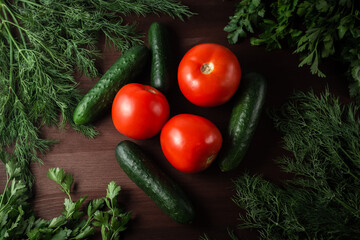 green cucumbers tomatoes and herbs on a wooden table