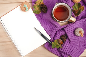 flat lay autumn notebook with fountain pen, purple sweater, metal tea mug with oak leaves, pine cones, knitted pumpkins