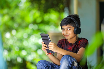 Indian / asian boy listening music or learning on mobile phone
