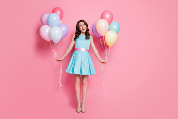 Full size photo of pretty lady festive event prom party hold both arms many air balloons dreamy look empty space wear blue mini dress skirt high-heels isolated pastel pink color background