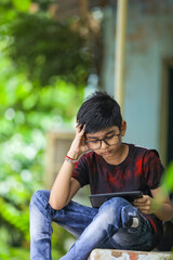 Indian / Asian Little boy studying online using mobile phone at home