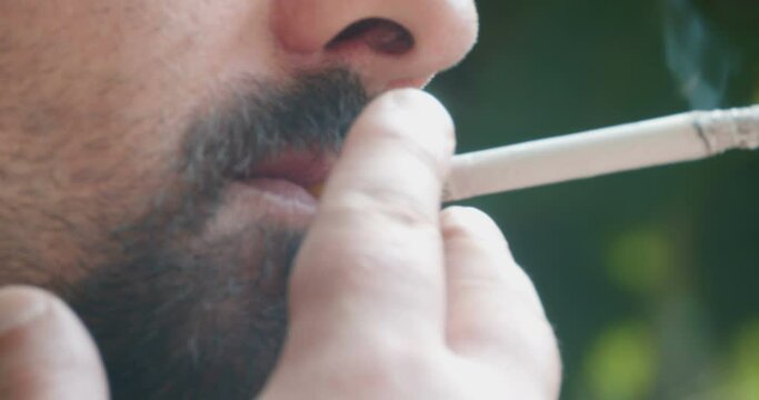 Man with beard is smoking a cigarette.