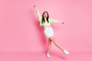 Full length photo of attractive youngster lady raise arms leg high dancing students party good mood wear casual crop pullover naked belly jeans skirt shoes isolated pink color background