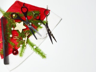 Christmas composition hairdressing tools and a spruce branch on the Santa Claus hat on a light background. Copy space.