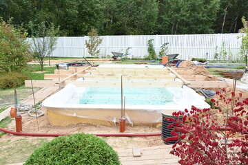 Fiberglass swimming pool construction building. Garden or backyard landscape works for swimming pool installation.