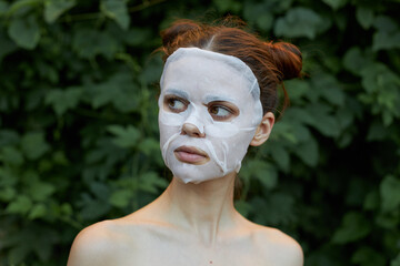 Beautiful woman cosmetic mask rejuvenation bushes in the background