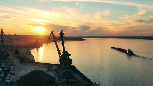 Sunset waterscape with loading port and a barge