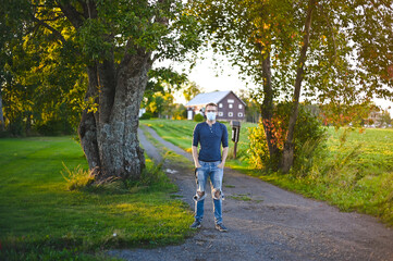 Obraz premium portrait of attractive nerd in long sleeve glasses and protective face mask outside in the park at sunset