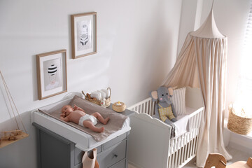 Cute little baby on changing table in room