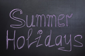 Phrase SUMMER HOLIDAYS written on black background. School's out