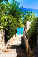 Widok ma lazurowe morze Adriatyckie, wąska dróżka prowadząca na plażę wśród...